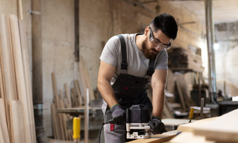 carpintero en su taller usando equipo de protección para carpinteros cortando un pedazo de madera