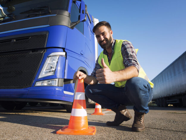 Hombre usando chaleco de prevención junto a un cono de vialidad