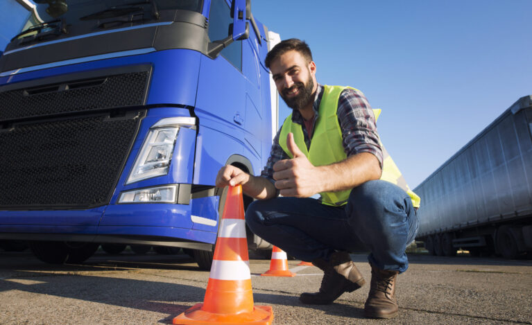 Hombre usando chaleco de prevención junto a un cono de vialidad